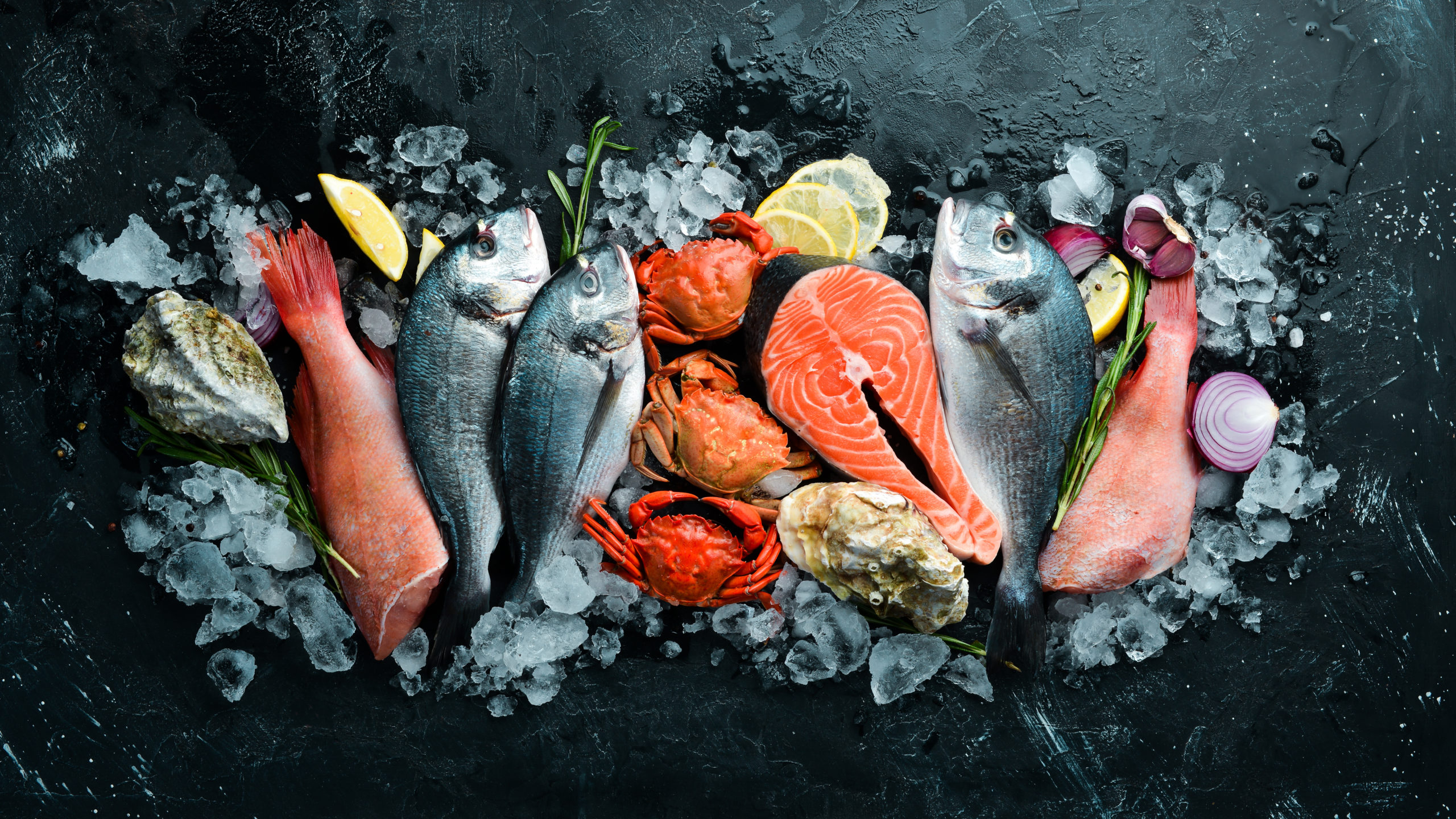 Seafood: Dorado, salmon, crab, grouper, oysters. On a black ston